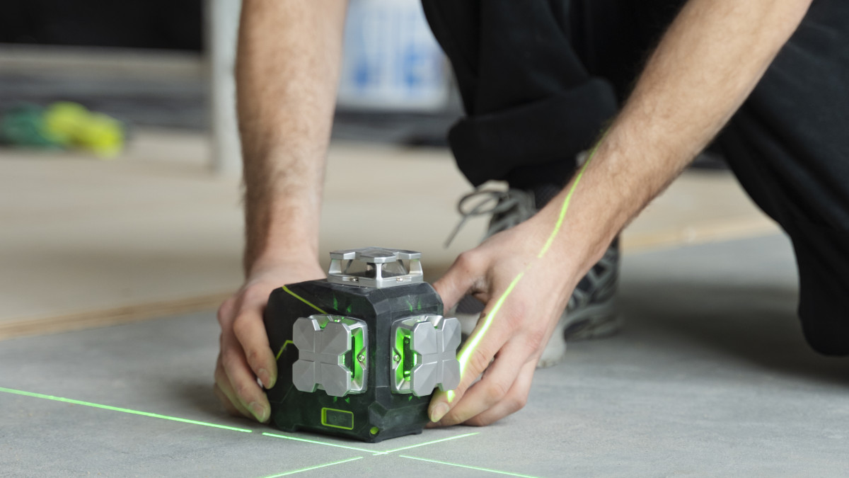 un professionnel dépose un niveau laser sur le sol avant d'entreprendre des travaux